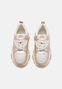 Lace-up sneakers in beige and white, featuring a textured upper with silver accents, metallic details, and a chunky rubber sole.