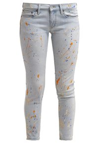 Jeans ajustados de color azul claro con salpicaduras de pintura en naranja, azul y beige distribuidas de manera uniforme en el frente y las piernas.