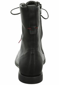 Bottine en cuir noir avec une finition texturée, fermeture éclaire à l'arrière et coutures rouges accents. Design à bout rond et à talon bas.