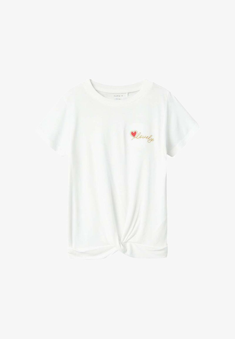 T-shirt blanc à manches courtes avec un ourlet noué. Présente un petit cœur rouge et le texte doré "lovely" sur la zone gauche de la poitrine. Tissu doux.