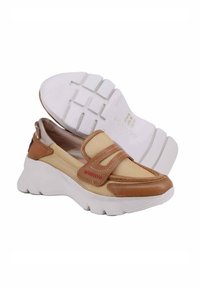 Scarpe slip-on beige con accenti in pelle marrone, tomaia testurizzata e suola bianca spessa con una trama a disegno.