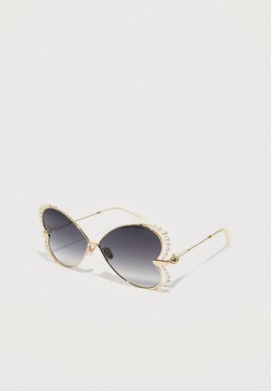 Occhiali da sole a forma di cuore con lenti grigie sfumate. Montatura dorata decorata con finte perle bianche. Bracci sottili con dettagli sottili.