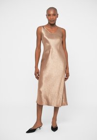 Satin midi kjole i lys brun, med spaghetti-stropper og en avslappet passform, med en lett tekstur og jevn finish. Sorte spisse ballerinaer.