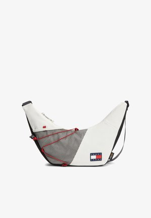 Biała torebka na ramię w kształcie półksiężyca z czarną siateczkową kieszenią, czerwonymi detalami sznurka i logo Tommy Jeans z przodu.