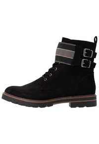 Stivale ankle in suede nero con suola robusta, dotato di una cinghia in tessuto a righe e due fibbie attorno alla caviglia, chiusura con lacci sulla parte anteriore.