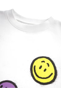 Maglione bianco in cotone con grandi design di faccine sorridenti colorate in giallo e viola, con contorni neri e una finitura strutturata.