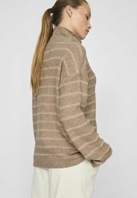 Rjav črtast pulover iz mehkega, teksturiranega materiala z visokim ovratnikom in rebrastim robom. Črte se izmenjujejo v svetlejših odtenkih za kontrast.