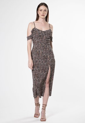 Schwarzes Midikleid mit floralen Mustern, schulterfreien Ärmeln, gerafftem Oberteil, Schlitz vorne und taillierter Silhouette. Tragen mit nude-farbenen Riemchenheels.