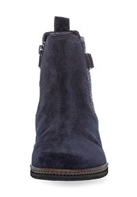Marineblauwe nubuck enkellaars met een gestructureerde afwerking, ronde neus, decoratieve stiksel en een bruine leren zool. Zijrits voor sluiting.