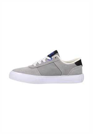 Grijze sneaker van suede en canvas, met een witte rubberen zool, zwarte hielaccent en blauwe logo-detail op de tong.