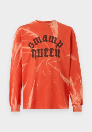 Oranžna dolgosleeva majica s tie-dye vzorcem v črni barvi z gotskim napisom "swamp queen" na sredini spredaj, z rebrastim ovratnikom in manšetami.