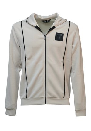 Felpa bianca con zip e dettagli neri. Presenta un cappuccio, tasche frontali e un'etichetta con logo sul petto. Tessuto morbido e liscio.