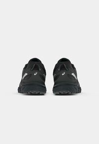 Black athletic shoes with a textured mesh upper, padded collar, and rubber sole featuring a distinct tread pattern. Reflective accents included.