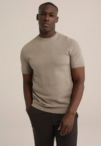 Krémový pletený svetr s krátkým rukávem a kulatým výstřihem, strukturovaná tkanina a žebrované akcenty na manžetách a spodním lemu. Přiléhavý střih.