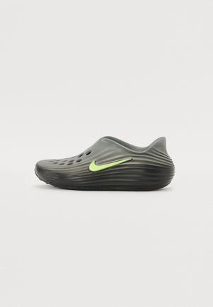 Nike jalatsid sügavas hallis, tekstureeritud pinnaga, ventilatsiooniavadega hingavuse tagamiseks ja erksroheline logo aktsent külgedel.