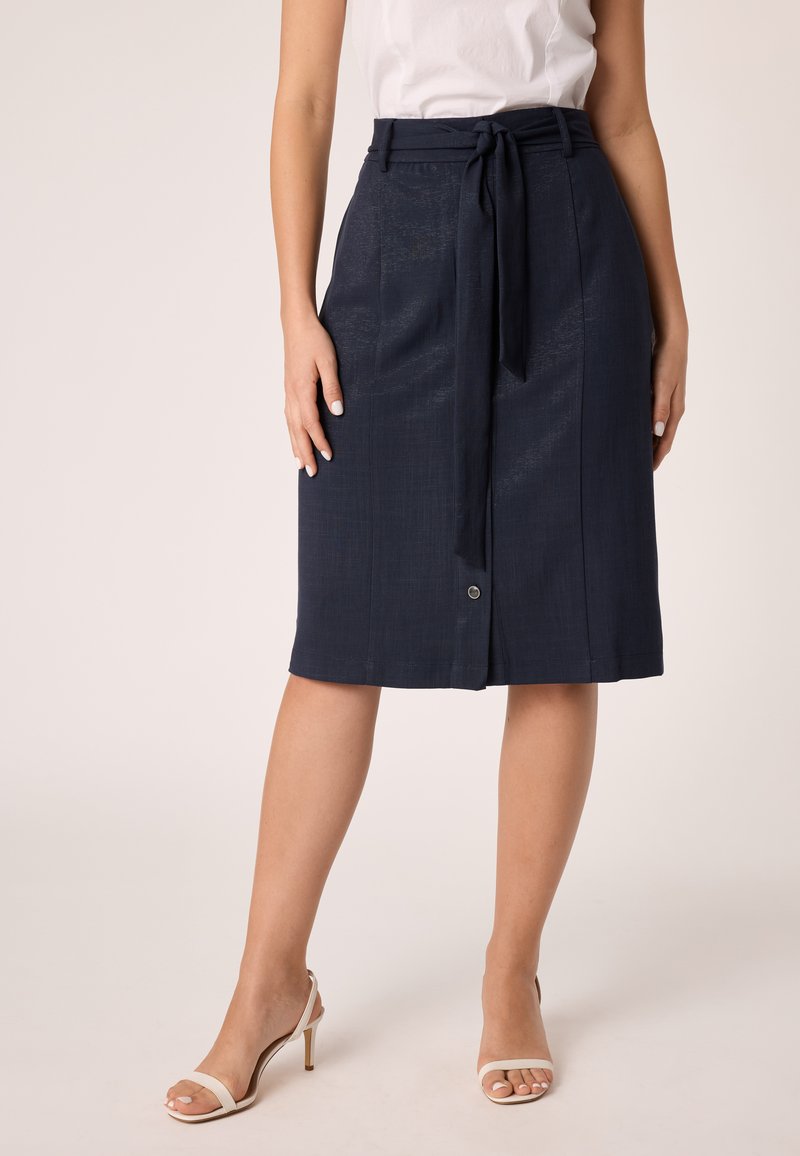 Gonna blu navy di lunghezza al ginocchio con cintura a nodo, due tasche frontali e un dettaglio con un bottone all'orlo. Il tessuto presenta una leggera texture.