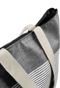 Schwarz-weiße, gemusterte Einkaufstasche aus strukturiertem Material, mit einem Reißverschluss und cremefarbenen Canvas-Trägern.