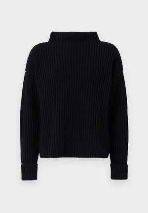 Svart strikket genser med høy hals, ribbet tekstur og brede ermer. Har en cropped passform og mansjetter med rullet kant.