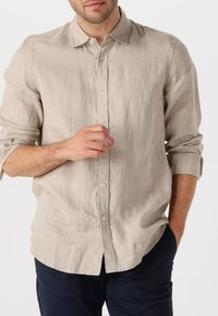Lys beige linned skjorte med button-down krave, lange ærmer oppe rullet, og en slim fit. Har en subtil tekstur og en lige kant.