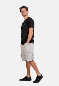 Schwarzes T-Shirt, graue Cargo-Shorts mit Seitentaschen und schwarze Sneakers; lässige Passform; natürliche Stoffstruktur; hellgraue Kontrastnähte.