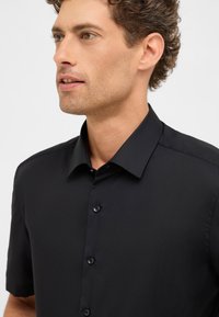 Korte mouwen zwarte shirt van gladde stof met een klassieke kraag, voorzien van vijf knopen aan de voorkant en een getailleerde pasvorm.