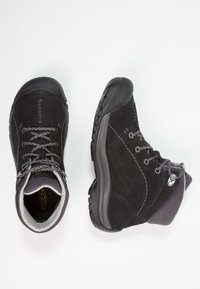 Botas de senderismo impermeables negras con materiales de ante y sintético, diseño de cordones, cordones grises, suelas de goma gruesas y cuellos acolchados.