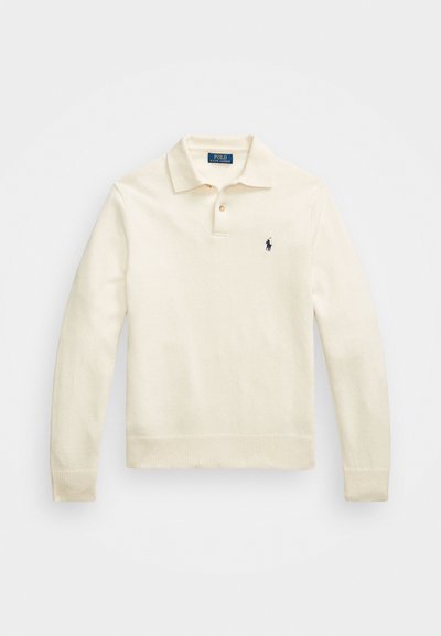 Κρέμα μακρυμάνικη πόλο μπλούζα με γιακά, τρία κουμπιά, ριπ περιμετρικά στις μανσέτες και το στρίφωμα, με ένα μικρό ναυτικό λογότυπο στο στήθος.