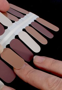 Farbmustern, die in Fächerform angeordnet sind; zeigt verschiedene Schattierungen von Beige, Braun und Creme mit matter Oberfläche auf schwarzem Hintergrund.