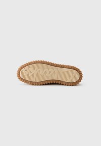 Rubber sole with a textured design, featuring circular protrusions along the edge and a visible logo on the bottom in a contrasting shade.