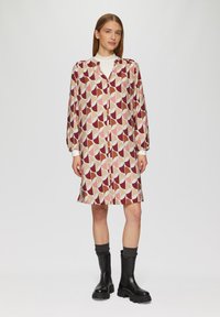 Langsleeve, knoop-up jurk met een geometrisch patroon in maroon, beige en roze. Gemaakt van een lichtgewicht stof, met een kraag en manchetten.