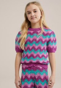 Vijoličasta in turkizna pletena majica z valovitim dizajnom, kratkimi pufastimi rokavi in rebrastim izrezom. Uparjena z ustreznimi krajšimi hlačami, ki imajo podobne vzorce.