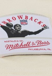 NFL Throwbacks-Patch mit einem schwarz-weißen Bild eines Spielers, der einen Football wirft, roten und weißen Text auf einem cremefarbenen Stoffhintergrund.