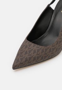 Chaussure à bout pointu marron à motif, avec un matériau texturé, un design à bride arrière ouverte et un intérieur noir.