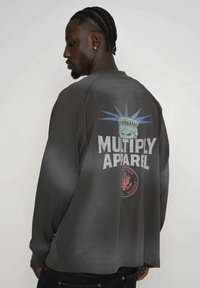 Sivá mikina s veľkým grafickým zobrazením Sochy slobody a textom "MULTIPLY APPAREL". Dlhé rukávy a voľný strih.