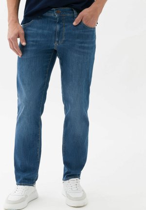 Blue denim jeans with a straight cut, five-pocket design, and subtle stitching details. Worn with white sneakers on a plain background.