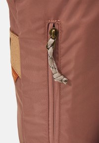 Rose-colored fabric bag featuring a side zipper with a beige textured slider and a cork accent. Smooth surface with subtle sheen.