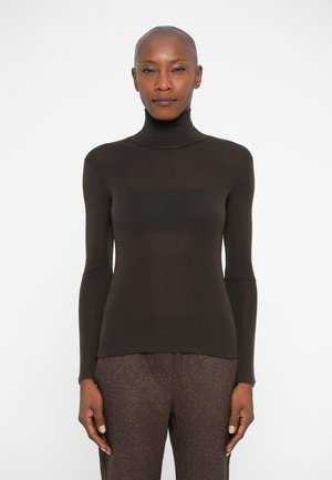 Brauner Rollkragenpullover mit langen Ärmeln, aus einem weichen, leicht strukturierten Material. Schmale Passform. Kombiniert mit gemusterten braunen Hosen.