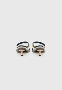 Marineblå sandaler med gullakkenter, med bakre stroppdesign og en liten, metallisk hæl. Teksturert materiale med et minimalt mønster.