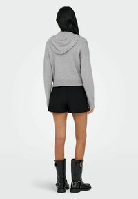 Hall väikese kapuutsiga hall lühike pusa, millel on kooritud soonik, koos mustade lühikeste pükstega ja mustade nahast kõrge säärega saapadega, millel on rihmad.