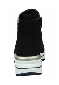 Bottines noires en daim, avec fermeture éclair, semelle blanche épaisse avec un accent métallisé et un design à bout arrondi.
