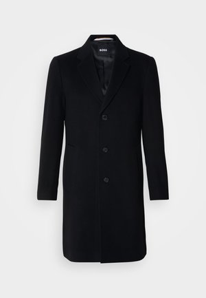 Manteau en laine noire avec un col cranté, design à un bouton, trois boutons et deux poches latérales. Texture lisse, détails minimes.