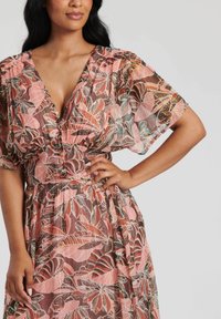 Abito lungo floreale con un motivo rosa e marrone, tessuto leggero e trasparente, scollatura a V e maniche a sbuffo con dettagli arricciati.