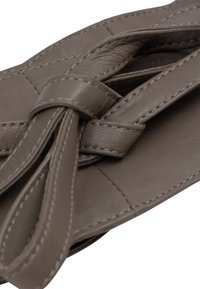 Hnědá kožená taška s uzlovým popruhem, hladkou strukturou a prošívanými detaily. Design je strukturovaný s obdélníkovým tvarem.