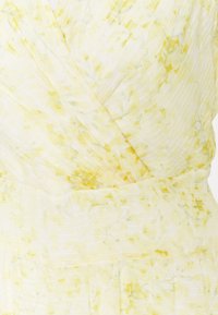 Wrapklänning i lätt tyg med ett gult och vitt blommönster samt fina vertikala ränder. Mjuk textur och flödande design.