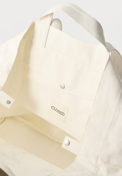 Εσωτερικό μπεζ τσάντας ώμου από καμβά με τσέπη με κουμπί και ραμμένη ετικέτα που αναγράφει "CLOSED".
