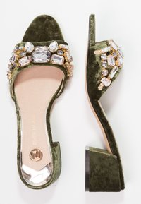 Vihreät samettiset korot mulesit nelikulmaisella varvalla. Yläosa on koristeltu eri värisillä ja kirkkailla jalokivillä.