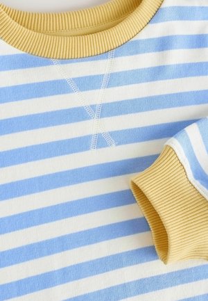 Stribet pullover i lyseblå og hvid med gul ribkant omkring hals og ærmer, med kontrasterende syninger og blød bomuldsstruktur.