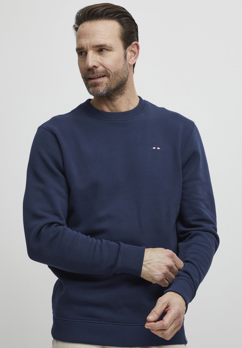 Maglione blu navy realizzato in tessuto misto cotone, con colletto tondo, polsini a costine e un piccolo dettaglio del logo sul petto.