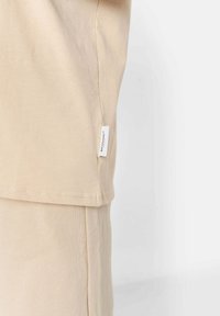 Beige overhemd met korte mouwen, gemaakt van zachte katoen en met een rechte snit, voorzien van een klein wit label aan de linkerkant.