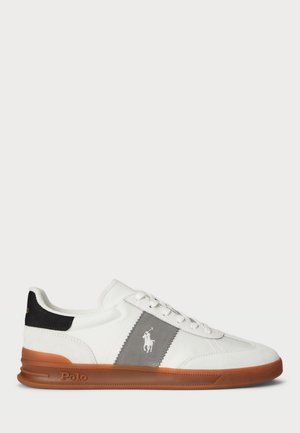 Weißer Low-Top-Sneaker mit brauner Sohle, grauem Seitenpanel, schwarzem Fersendetail und weißem Polo-Logo an der Seite.